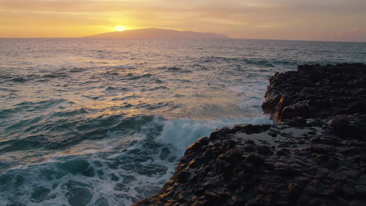 太阳落在戈梅拉岛上，海浪拍打岩石海滩的慢动作。海边近景，自然夏日风光视频素材