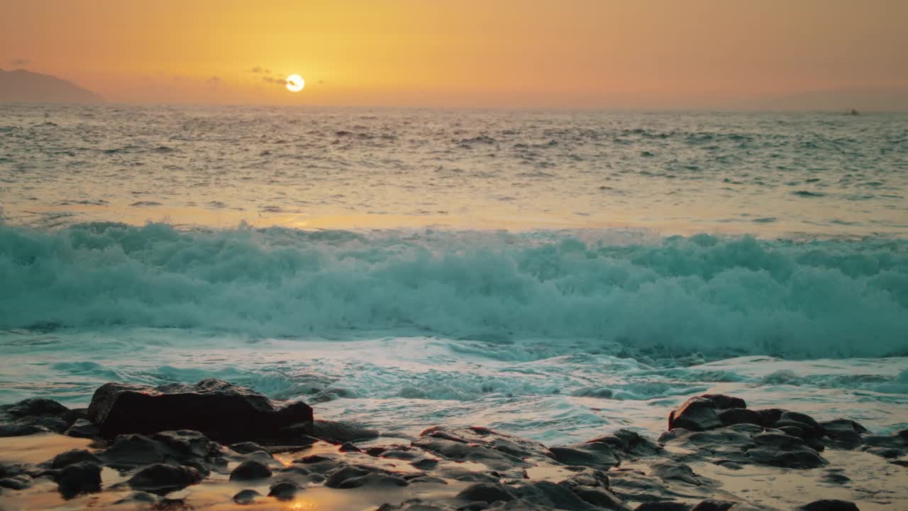 美丽的海景对着地平线，落日在海水上。近距离拍摄日落时飞溅的浪花。视频素材