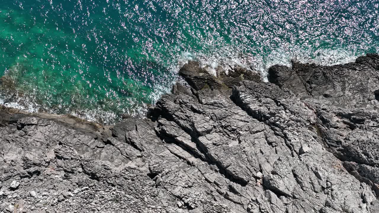 蓝色和翡翠色的大海拥抱着海湾的坚硬岩石，这是无人机拍摄的视频下载