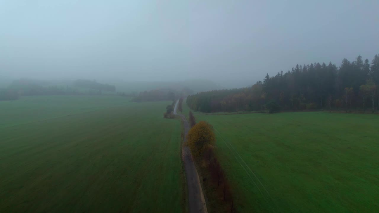 多雾天气时，无人机在田野和树木之间的道路上拍摄的照片视频素材