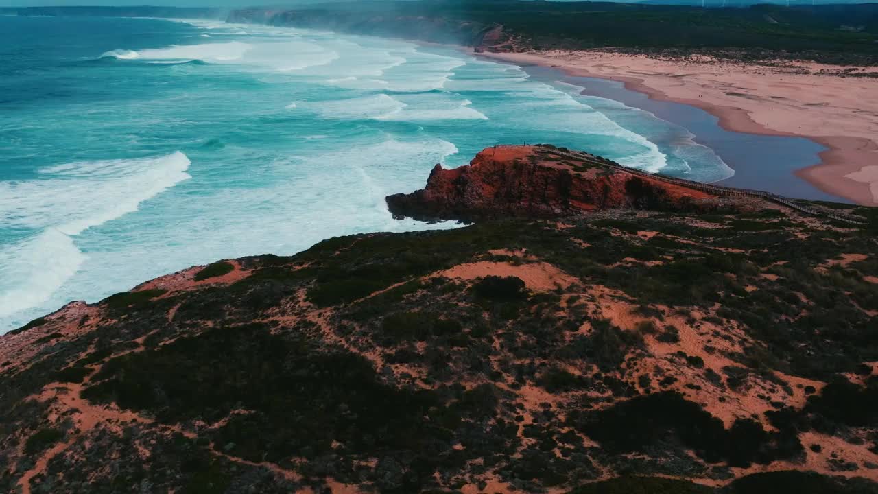 无人机拍摄的海浪在日落时飞溅在悬崖岛上的绿色草坪上视频素材