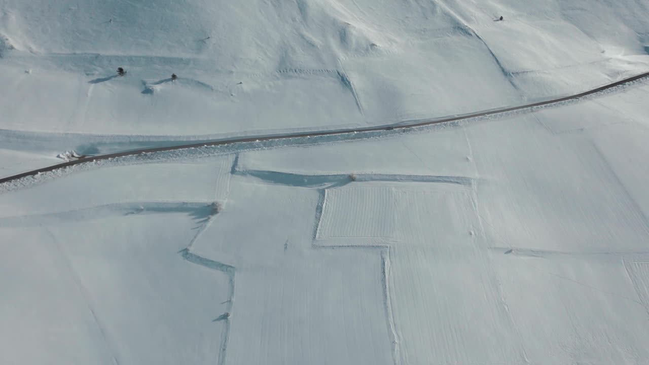 航拍视频显示，这条道路被冰雪覆盖的高大岩石山脉包围视频素材