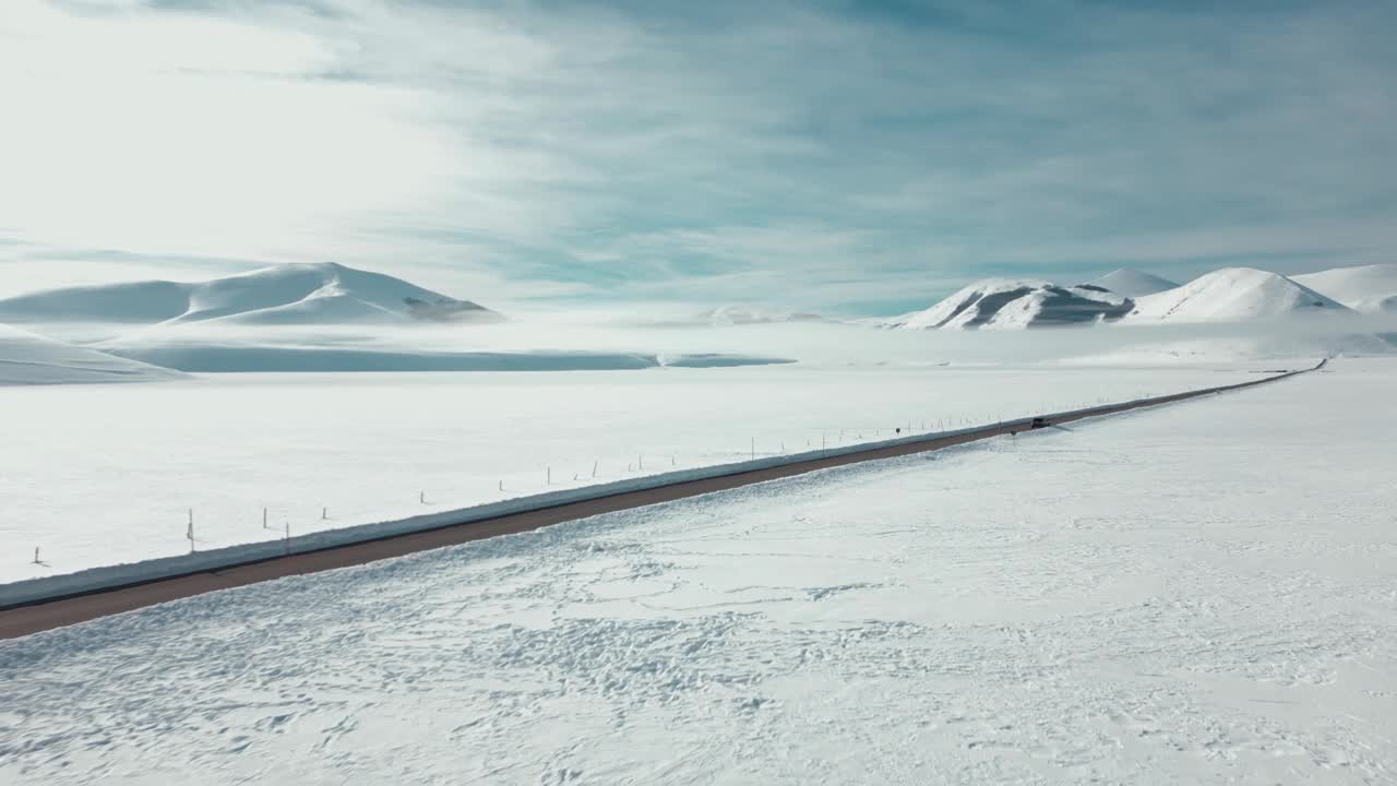 航拍视频显示，这条道路被冰雪覆盖的高大岩石山脉包围视频素材