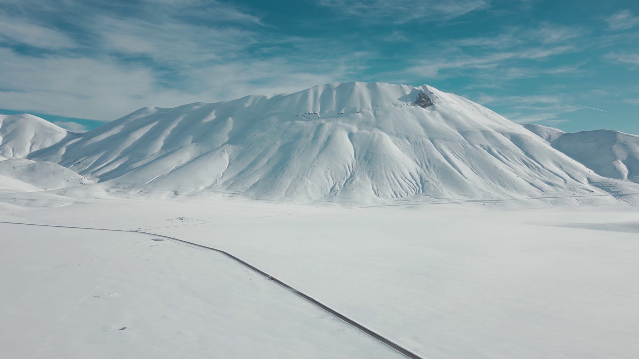 航拍视频显示，这条道路被冰雪覆盖的高大岩石山脉包围视频素材