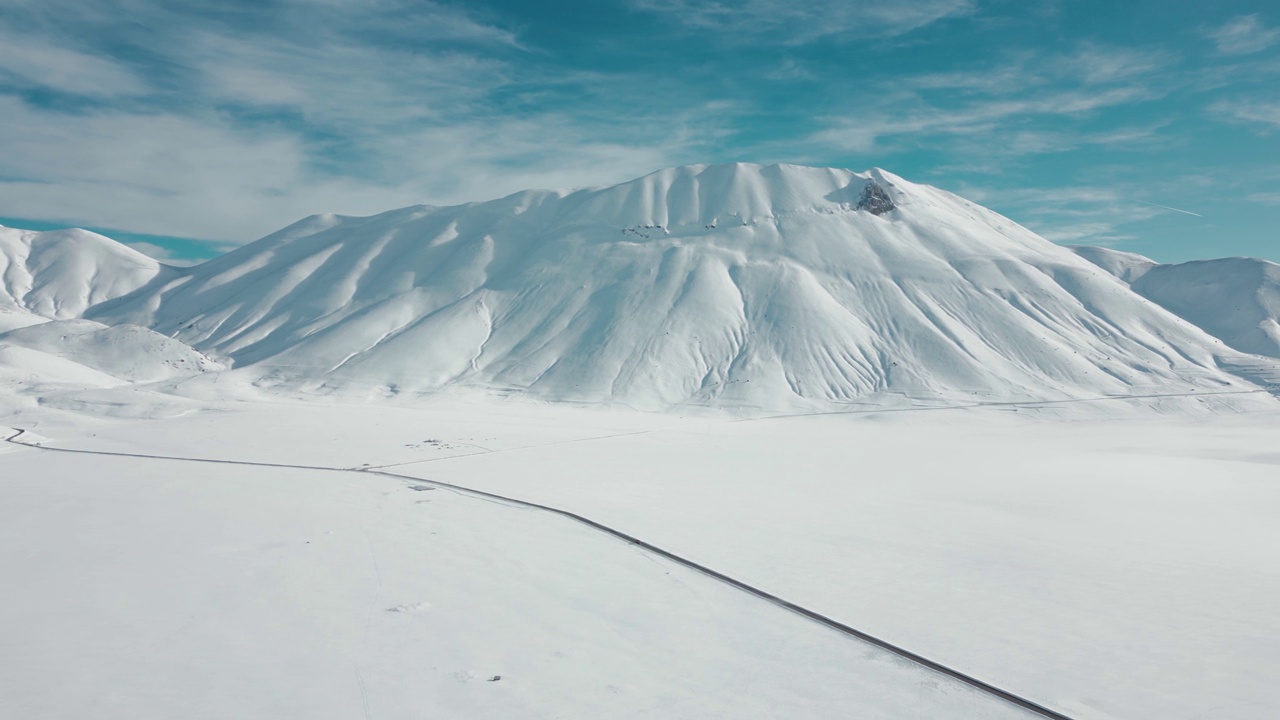 航拍视频显示，这条道路被冰雪覆盖的高大岩石山脉包围视频素材