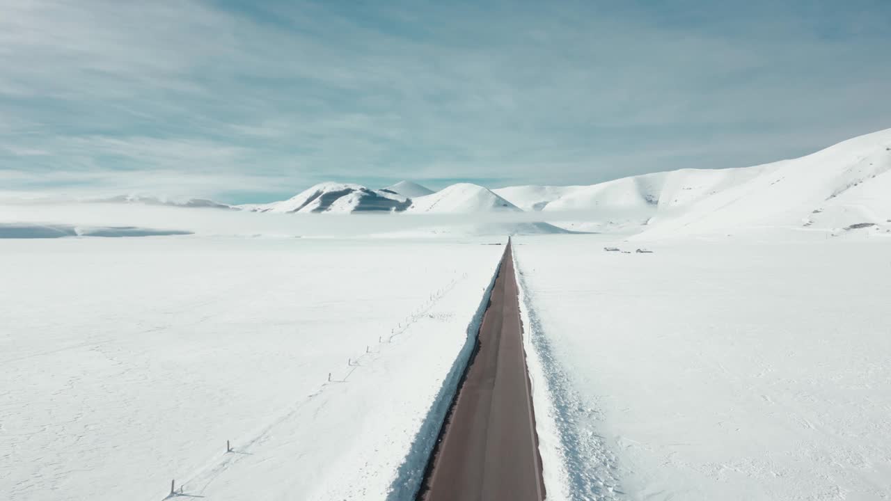 航拍视频显示，这条道路被冰雪覆盖的高大岩石山脉包围视频素材