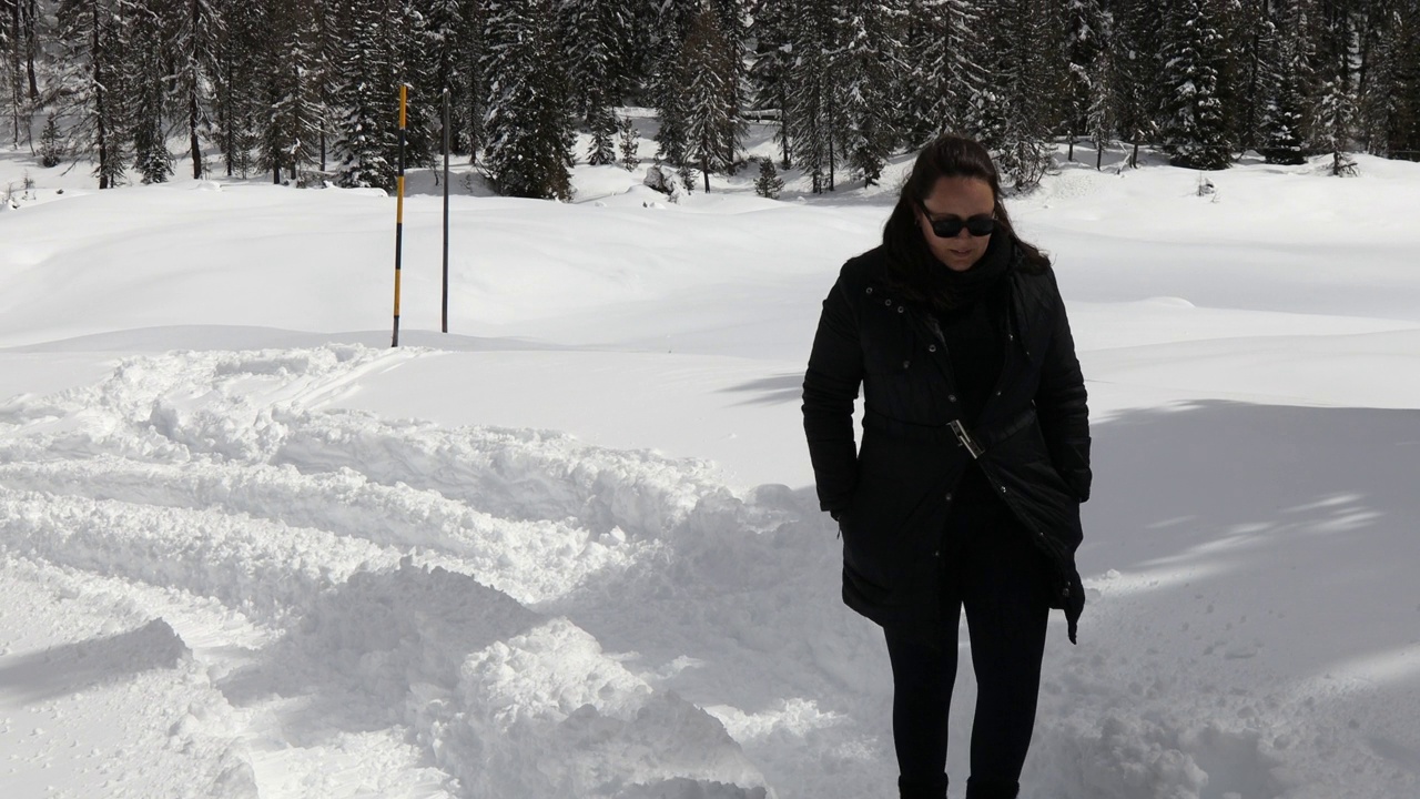 年轻女子走在米苏里纳路上，冒着大雪去拉瓦雷多村;白云石山脉、意大利视频下载