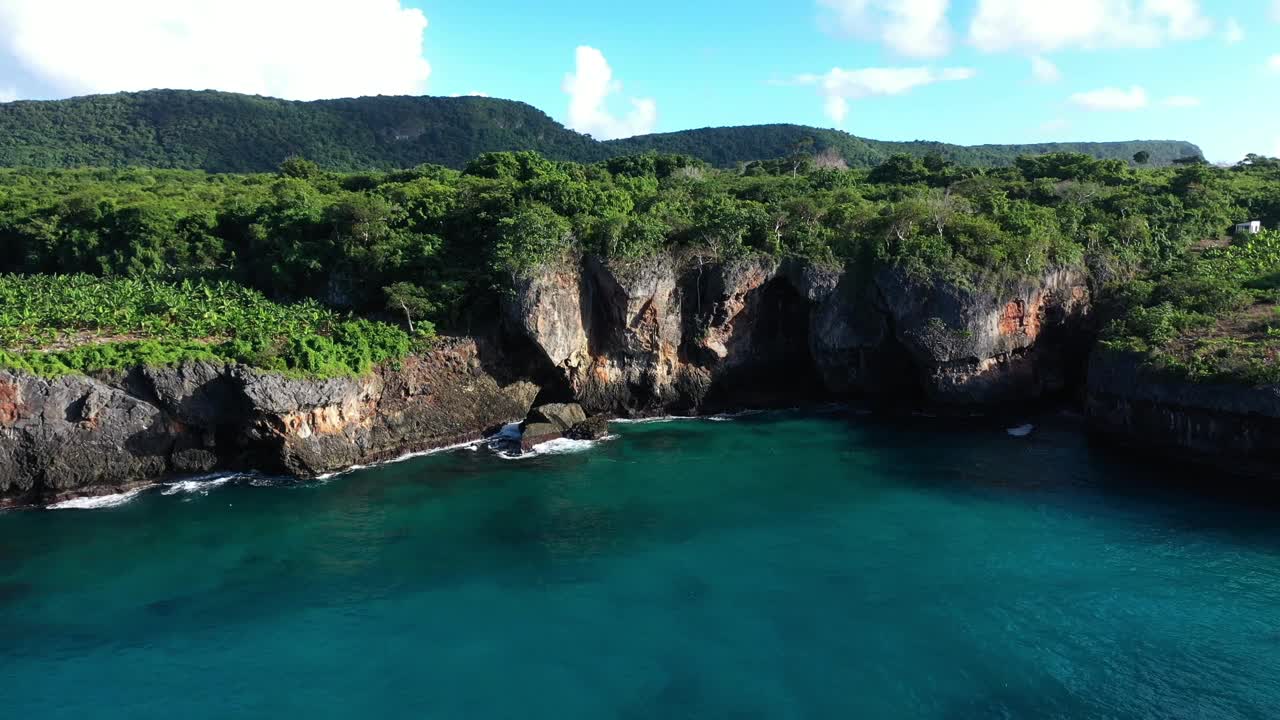 航拍视频显示海浪冲击着布满树木的岩石海岸视频素材