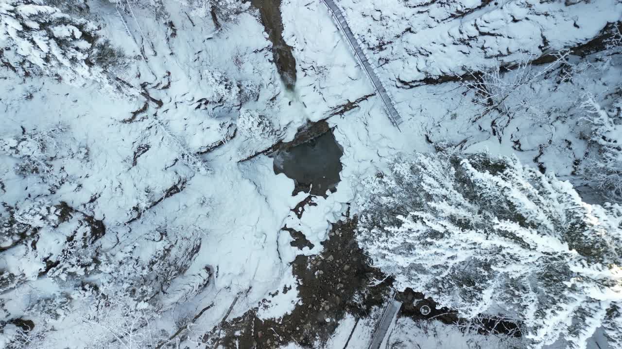 冬天，在奈塞尔旺瀑布的树木和岩石中，无人机在白雪皑皑的阿尔卑斯山上飞行视频素材