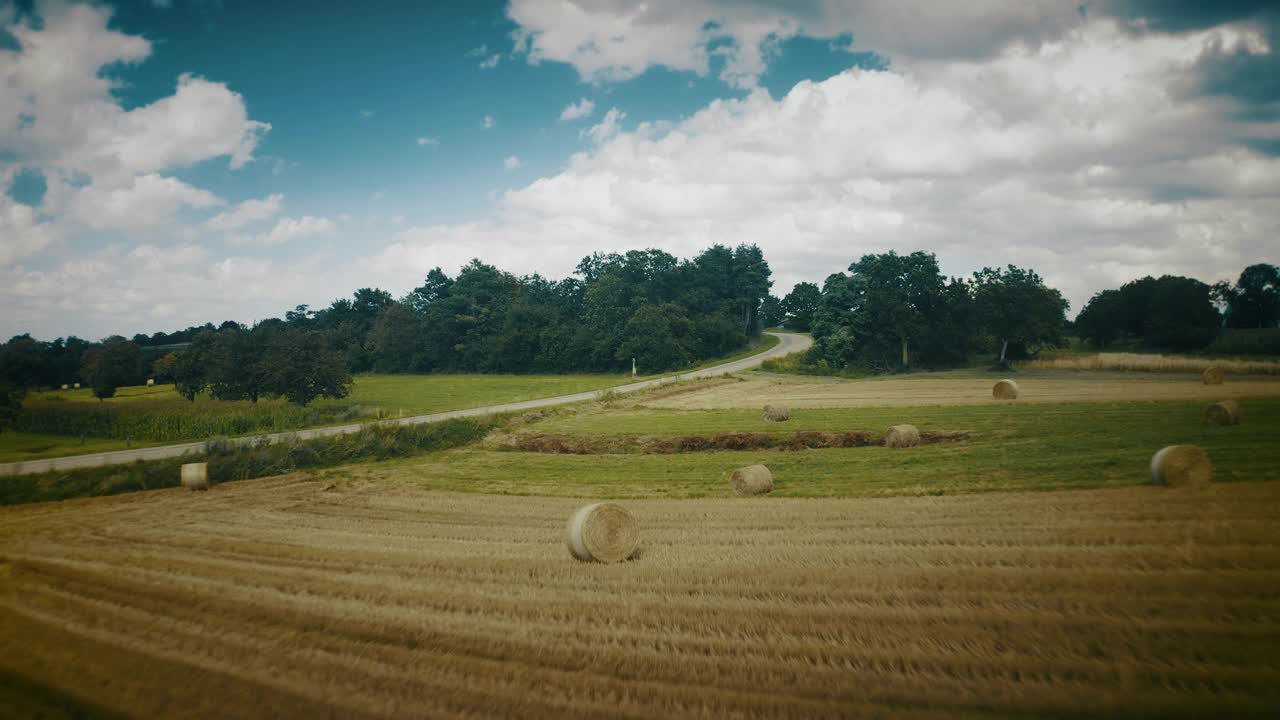 无人机镜头在绿色的草地和高速公路上驾驶汽车在蓝色多云的天空视频素材