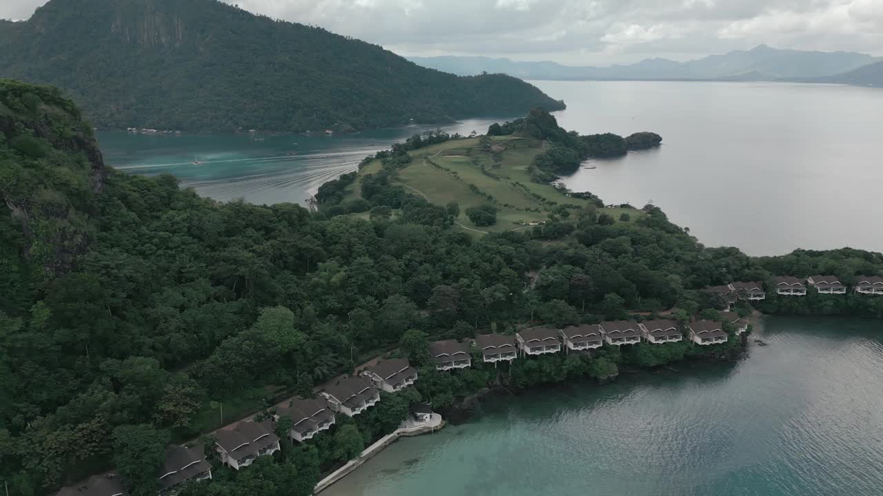 航拍的热带树木覆盖的山脉和海岸上类似的房屋视频素材