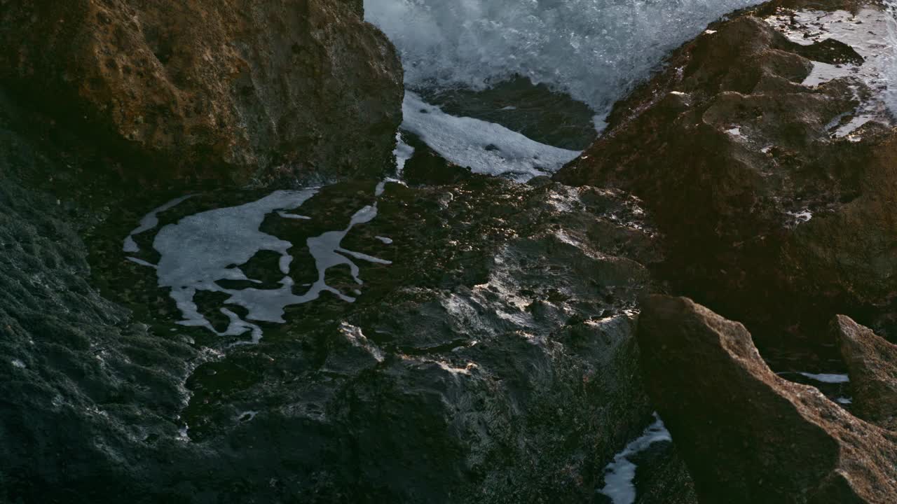 海洋溅起泡沫山外特写。白色的浪花被巨大的岩石打碎视频素材