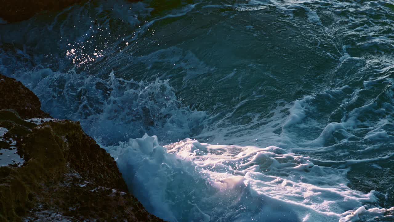 泡沫海浪冲击海岸外特写。汹涌的水流碾压着危险的岩石视频素材