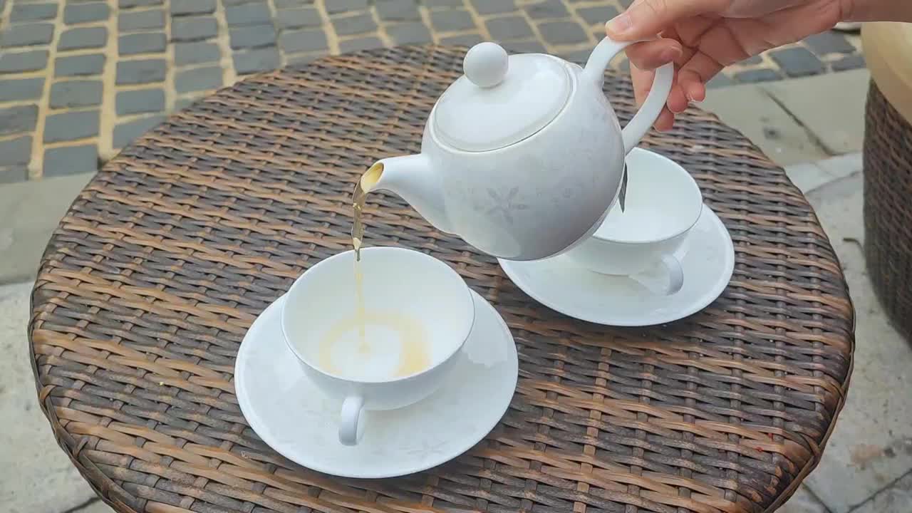 茶壶把茶倒进杯子里。视频素材