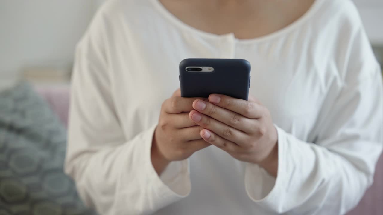 手的亚洲漂亮少女用手机发短信或聊天。年轻女子手的特写视频素材