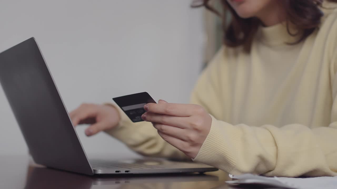 女性使用智能手机和笔记本电脑进行网上购物，在家用信用卡支付视频素材