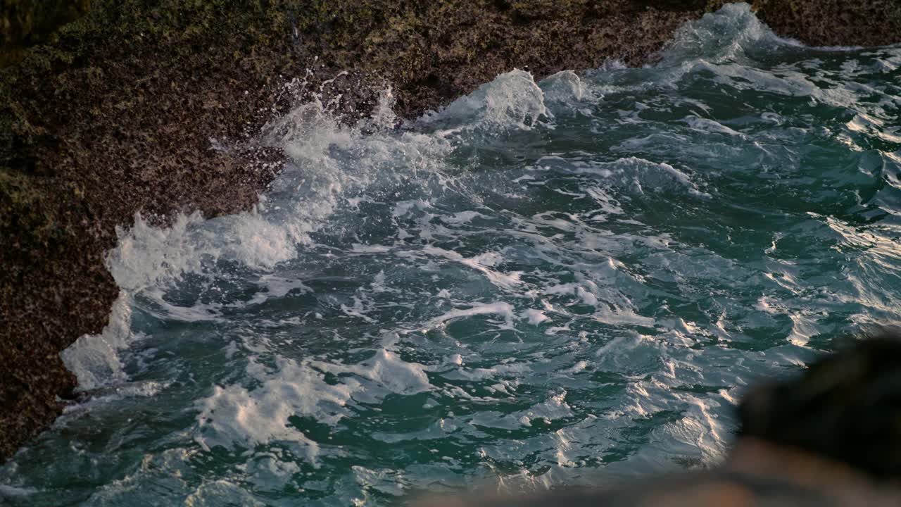 极端海浪粉碎海岸外特写。海水被火山石溅起视频素材