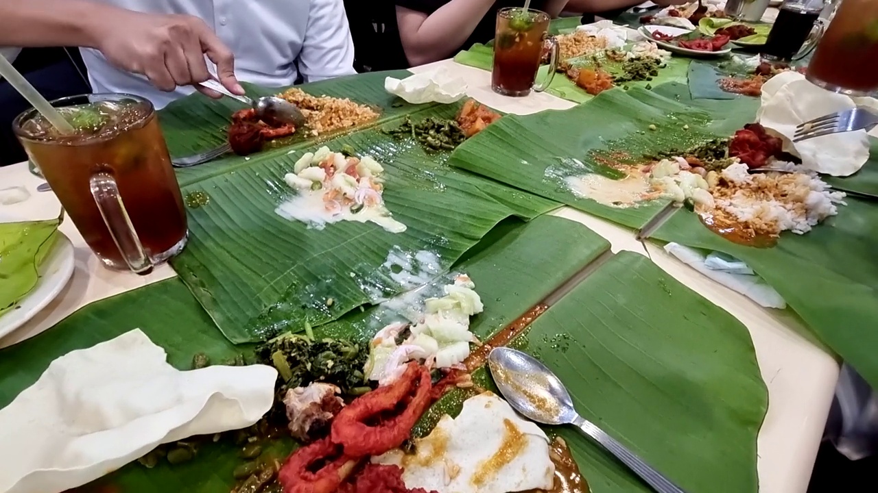 一群人在印度餐馆享用美味的香蕉叶饭或sadya，配上蔬菜和肉视频素材