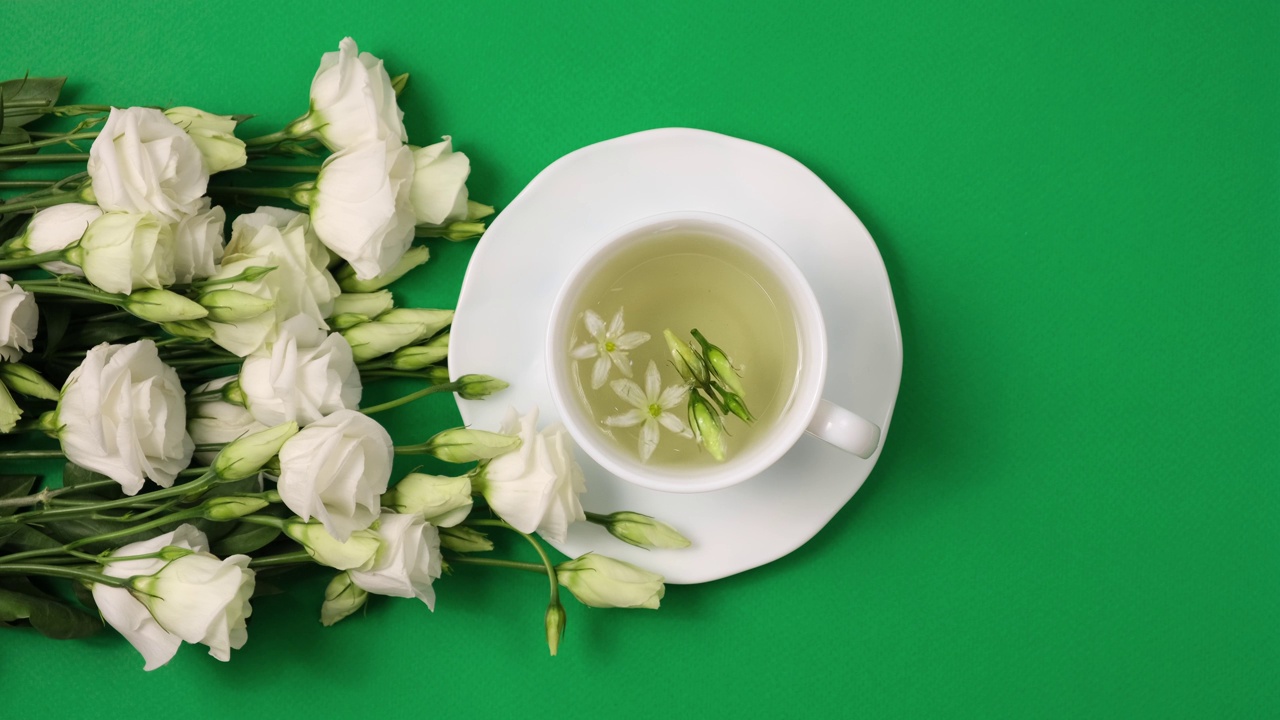 花卉茶。白色的杯子里有香浓的凉茶和百合花附近。下午茶时间。放松与花草茶，白色背景，顶视图，垂直视频视频素材