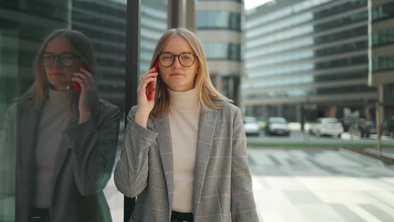 一位戴着眼镜的金发美女正在商务中心接听电话。女孩看了看表，开会迟到了视频素材