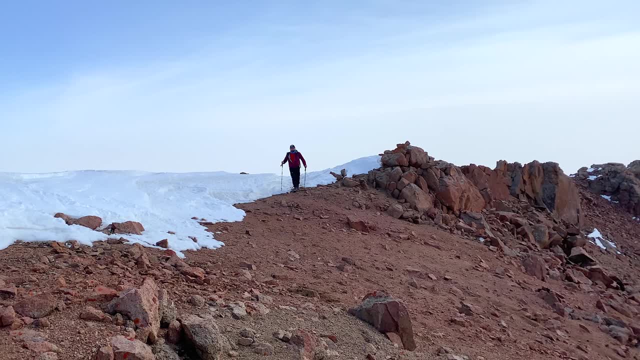 孤独的游客沿着山间小路走过巨大的岩石和积雪。美丽的山景。视频素材