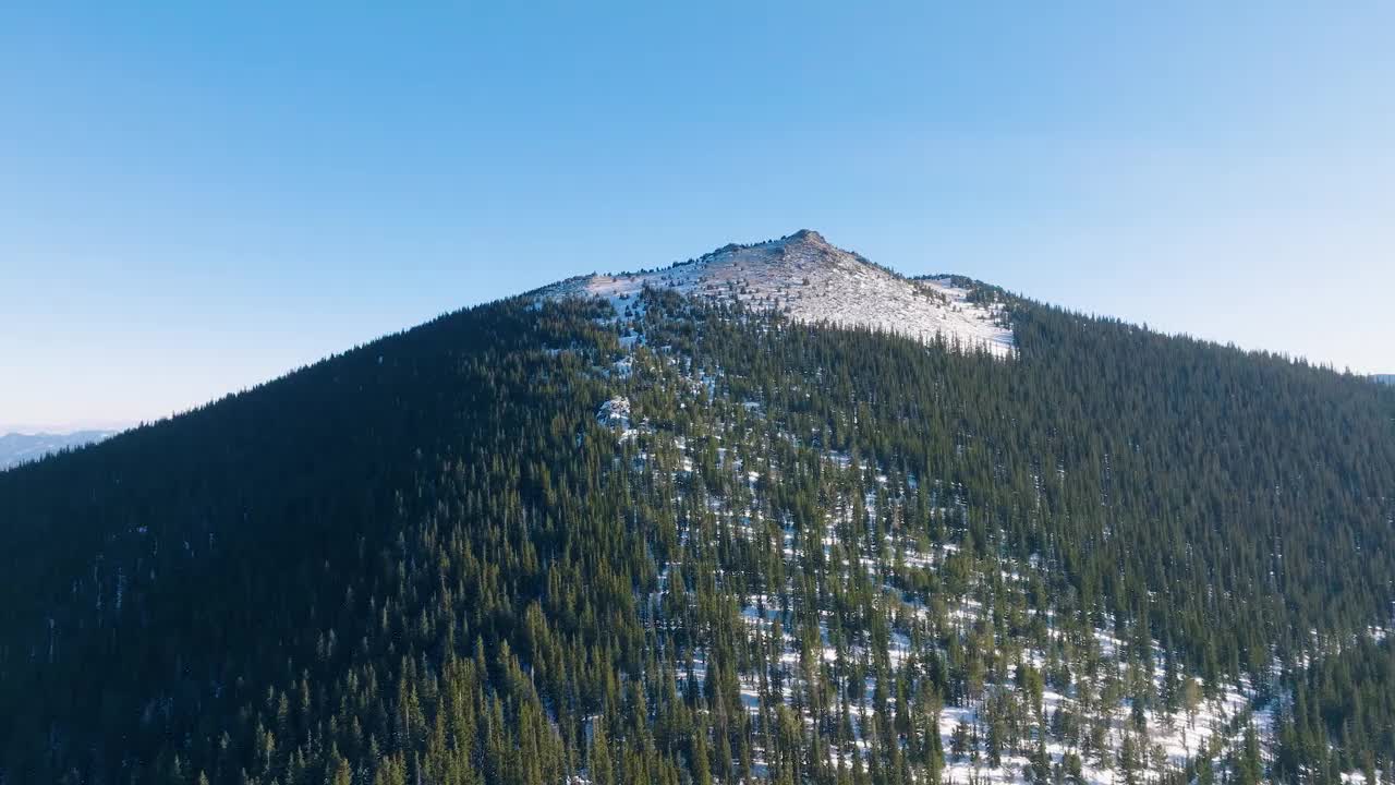 航拍视频，冬天岩石山脉被树木和明亮的雪覆盖视频素材