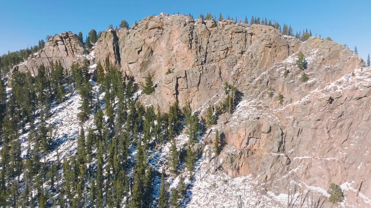 航拍视频，冬天岩石山脉被树木和明亮的雪覆盖视频素材