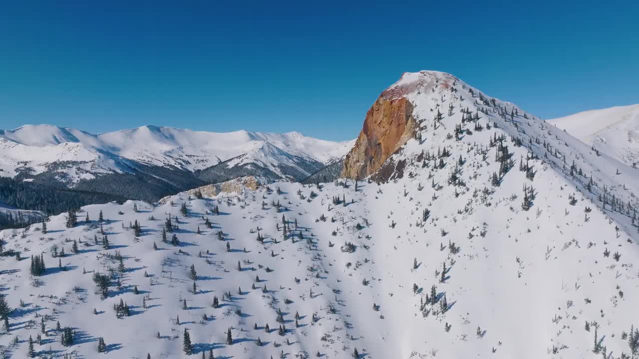 航拍视频，冬天岩石山脉被树木和明亮的雪覆盖视频素材