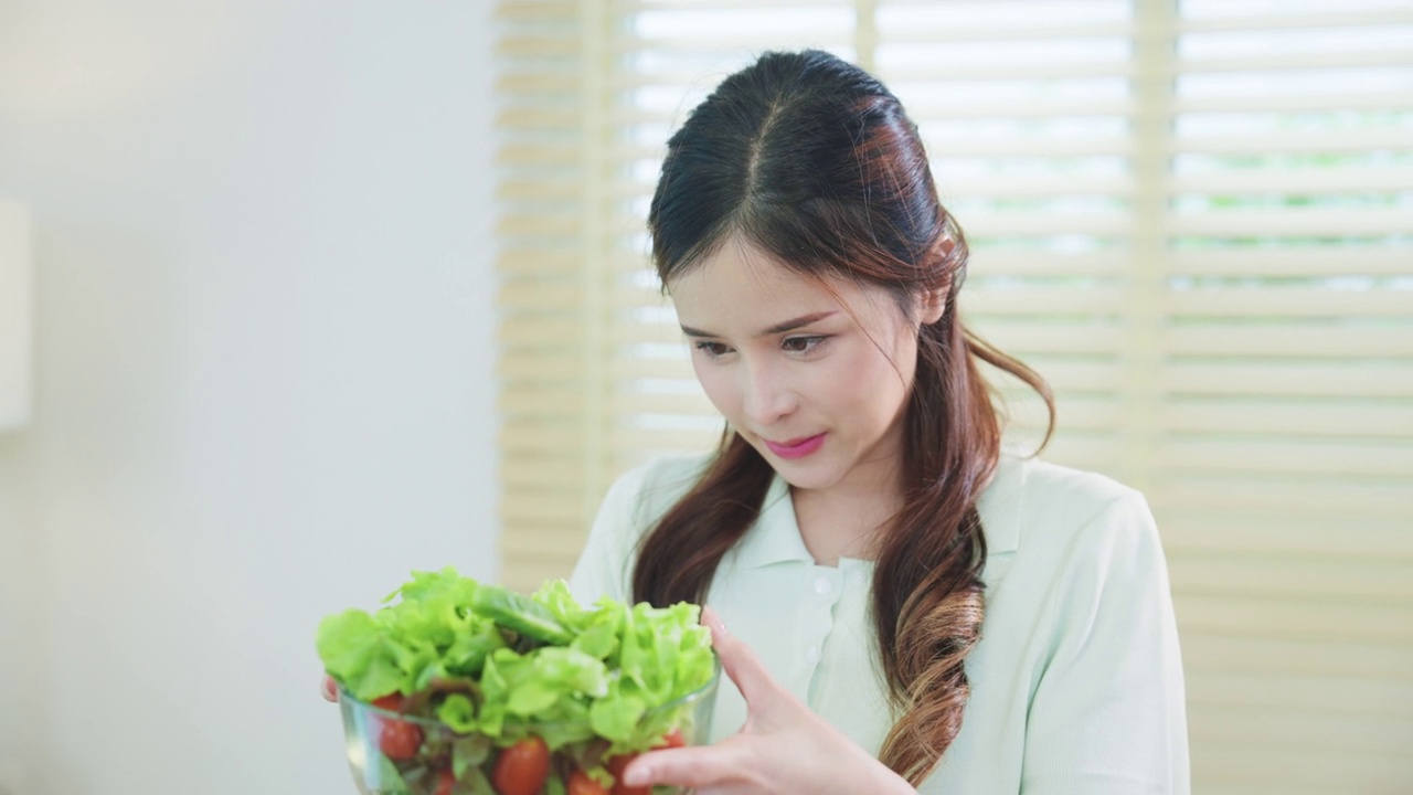 微笑的漂亮女人在厨房里拿着健康的沙拉。视频素材