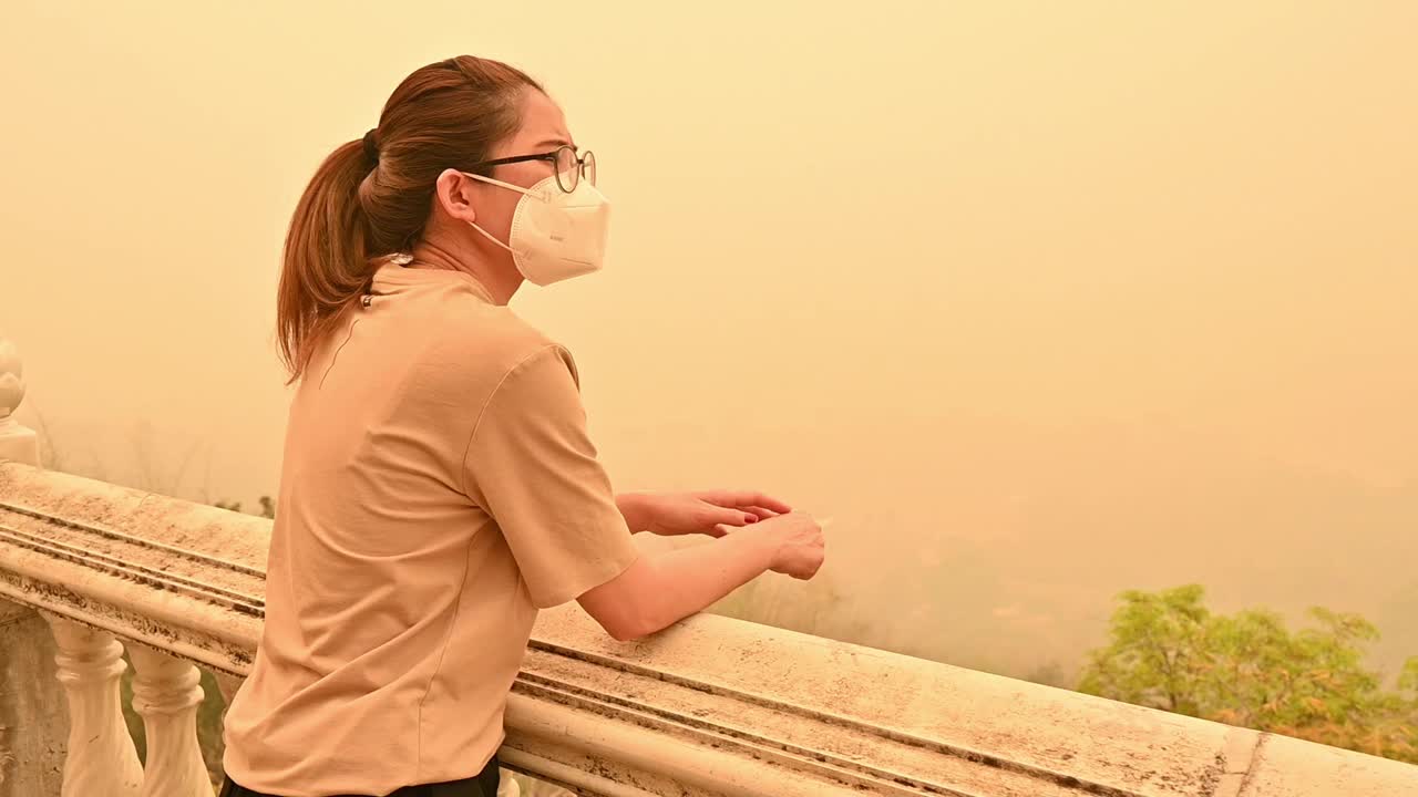 一名忧心忡忡的亚洲妇女戴着n95口罩，以防止严重的空气污染。视频素材