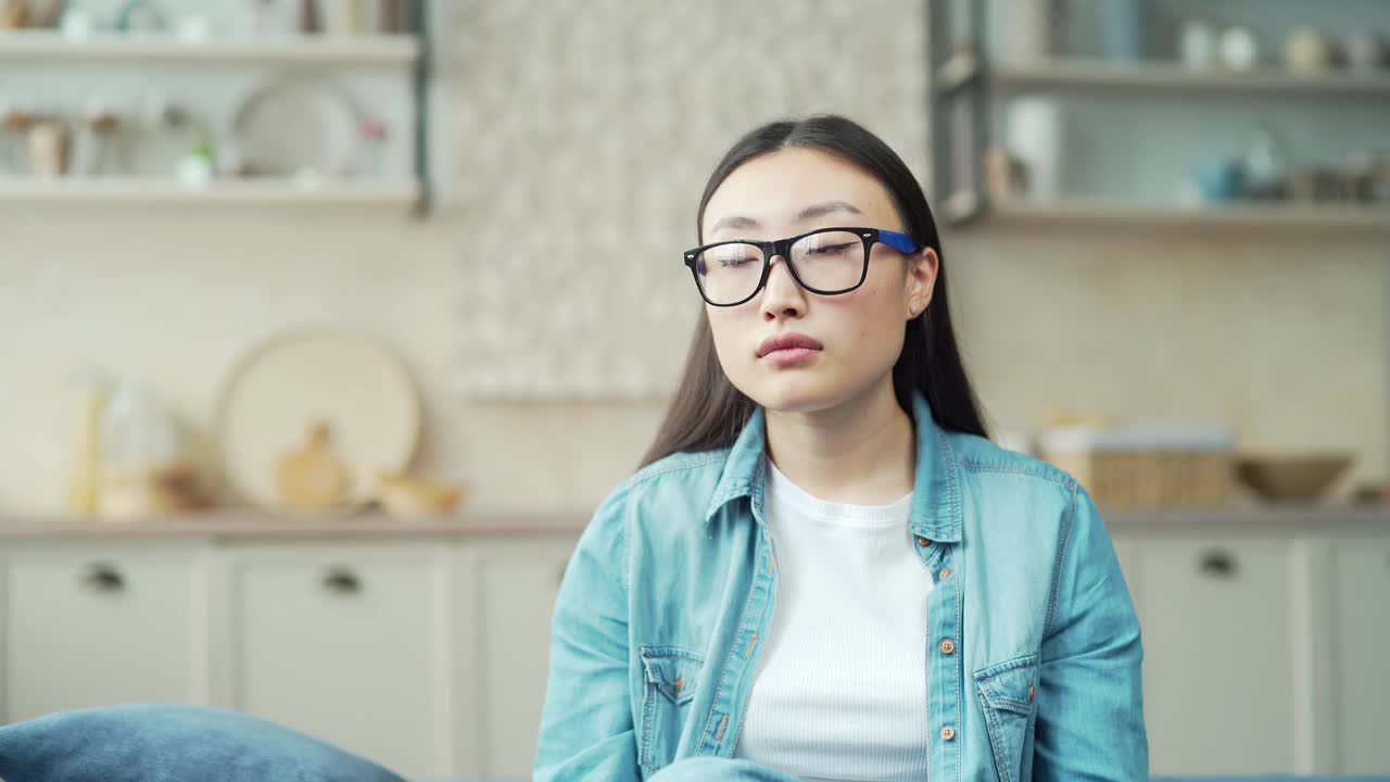 年轻的亚洲女子坐在客厅的沙发上感到头痛的特写视频素材