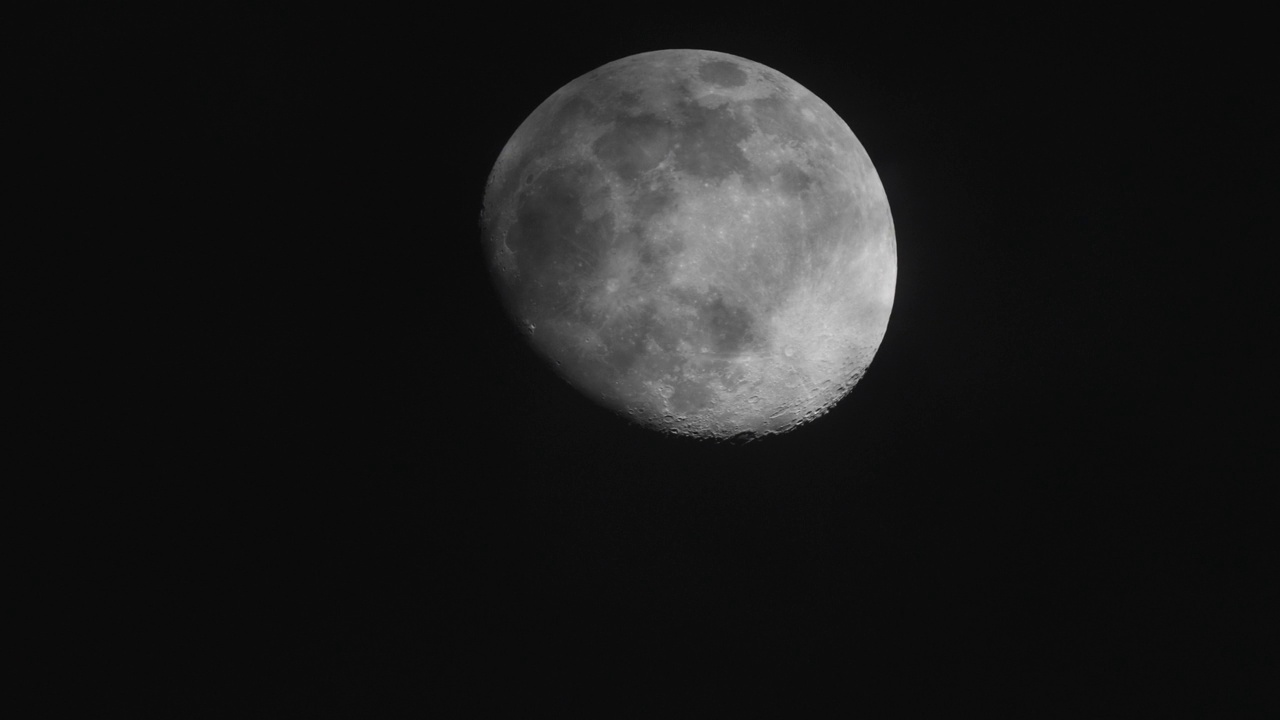 夜晚满月与黑色天空背景的特写，云彩移动，月光闪耀，长焦镜头4k慢动作镜头。视频素材