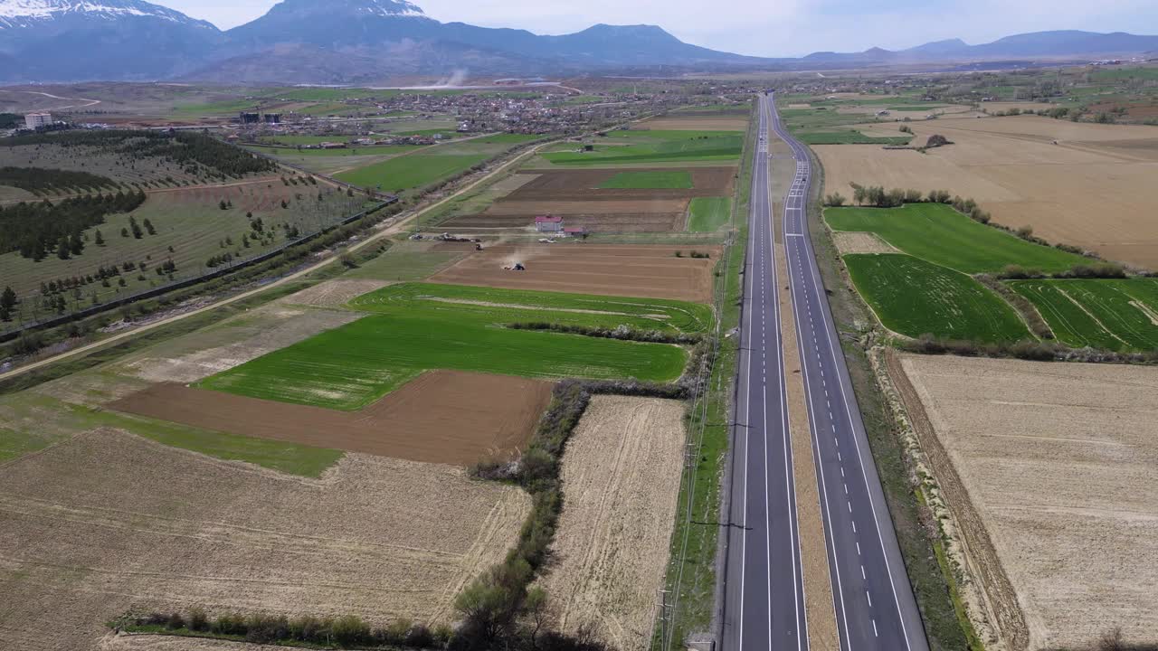 无人机拍摄的农田间高速公路上的拖拉机视频素材