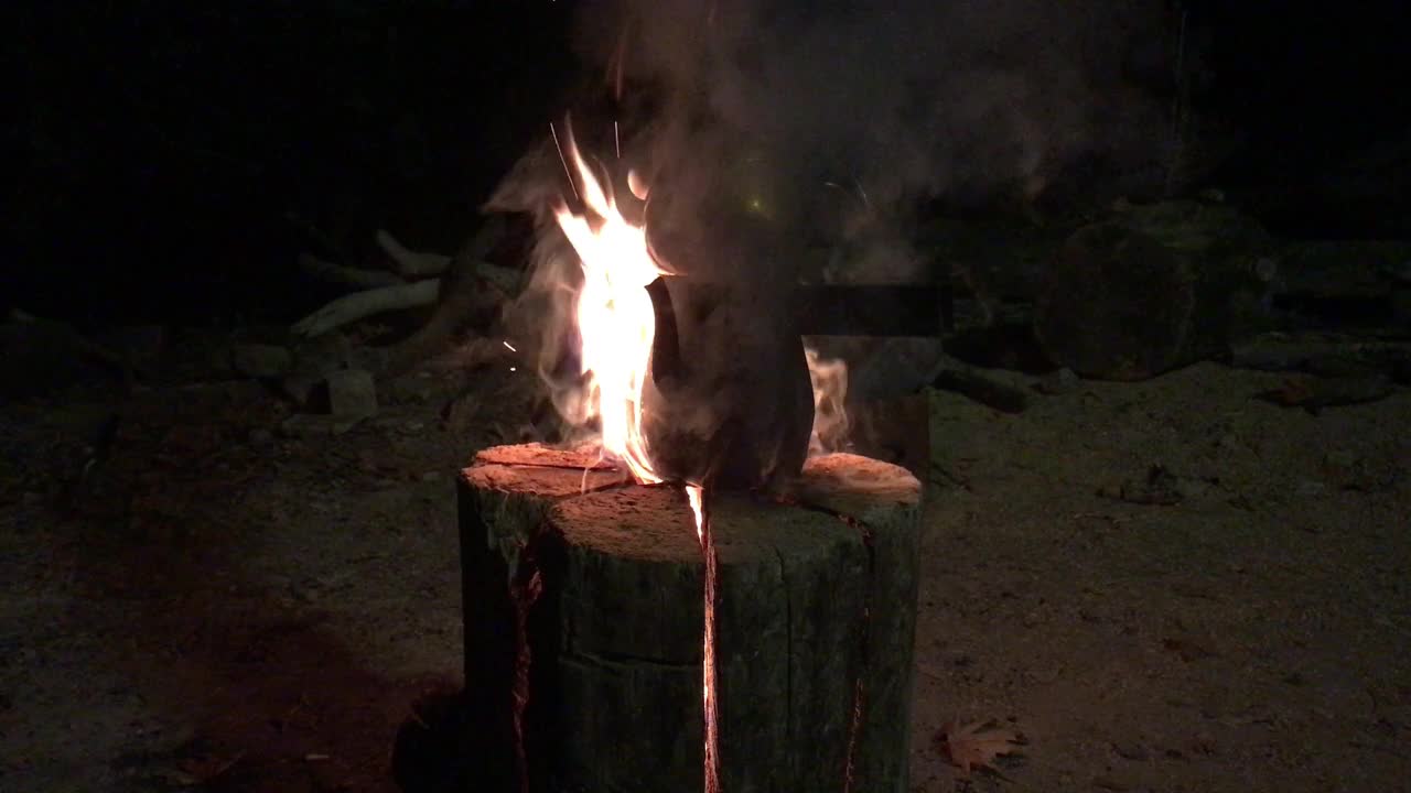 在垂直放置的树干上加热的茶壶，中间切开并燃烧视频素材