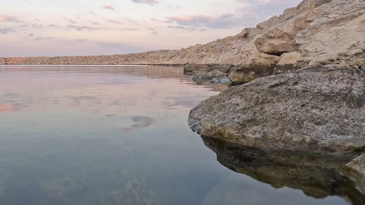 平静的泻湖和海石在傍晚的特写。天空在大海中的倒影。放松和假日氛围。4 k视频素材