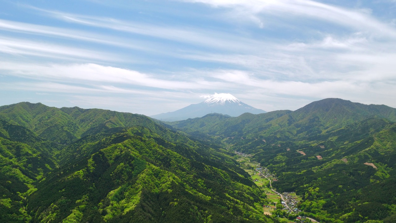 鸟瞰白雪覆盖的富士山在多士村清新的绿色中视频素材