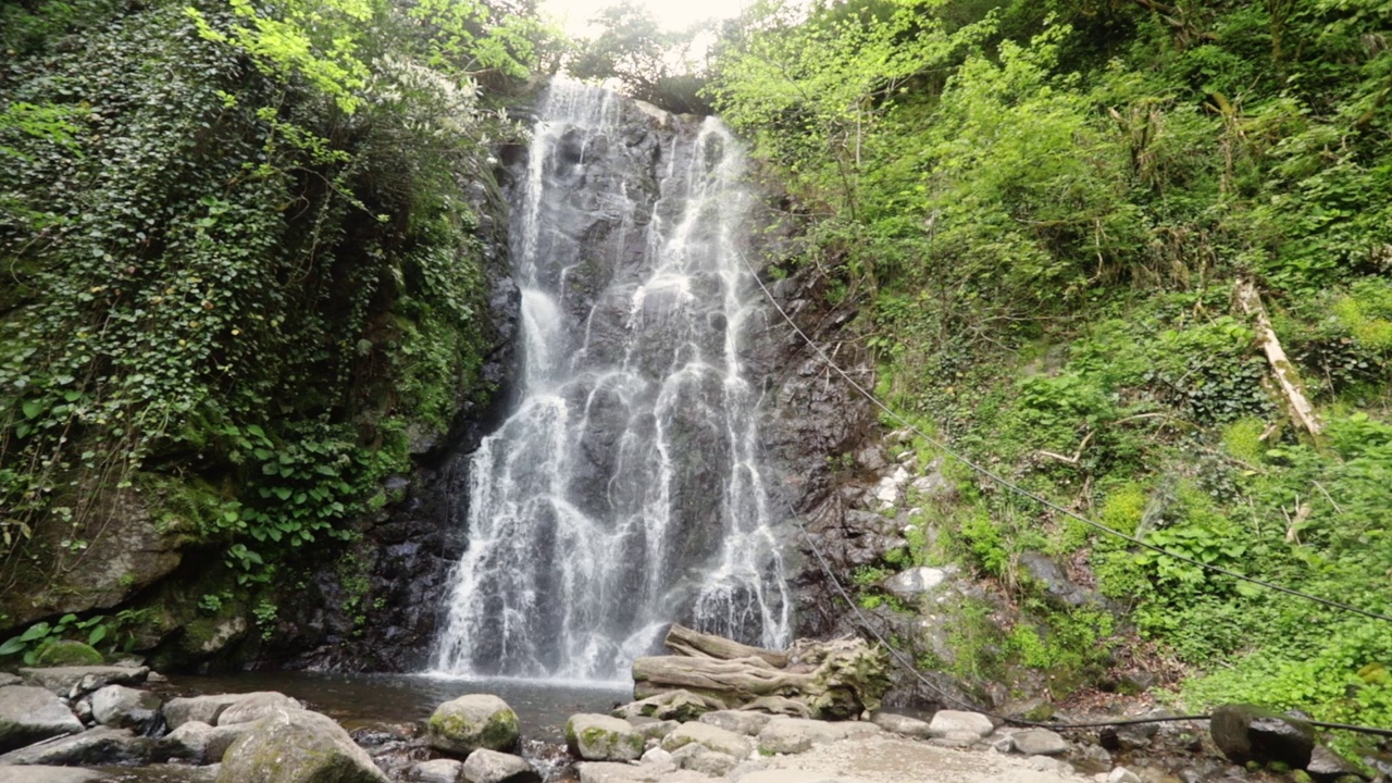 舒缓的瀑布在山上，水流从上面的岩石落在石头上视频素材