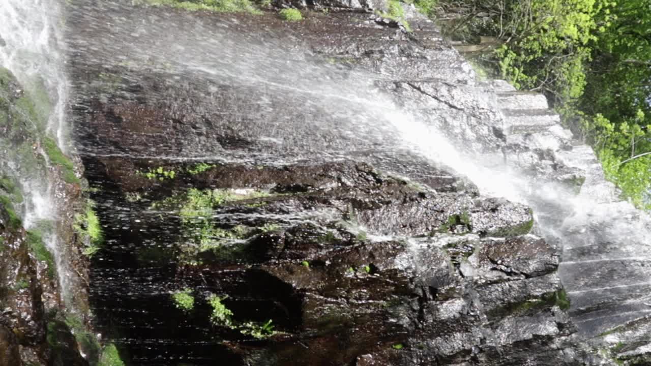 强大的瀑布坠入水晶般清澈的水潭，水流从岩石上落在石头上视频素材