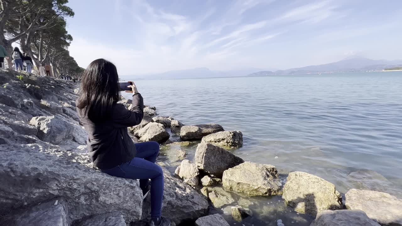 一个女孩在湖边用智能手机拍视频视频下载