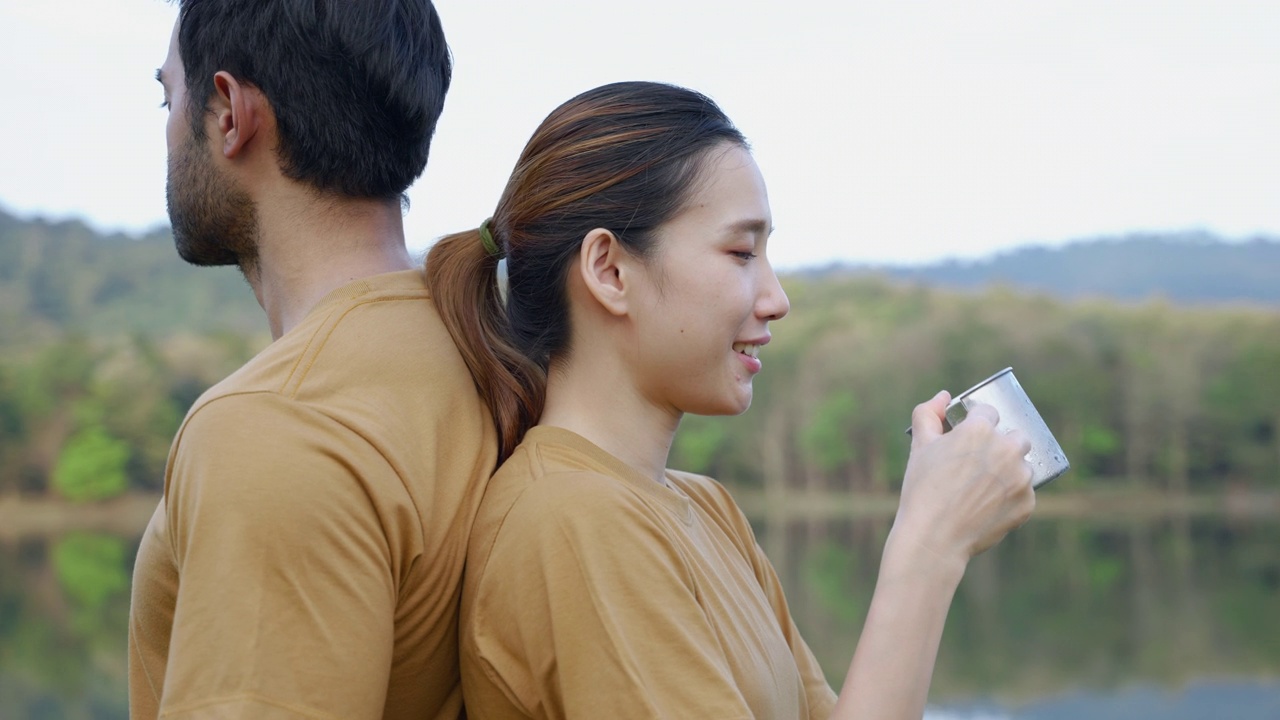 年轻的亚洲夫妇在湖边喝着早晨的咖啡，旅行的想法，放松视频素材