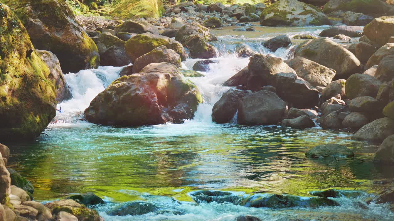 山河在阳光下流淌。水在自然公园的大岩石上流动视频素材