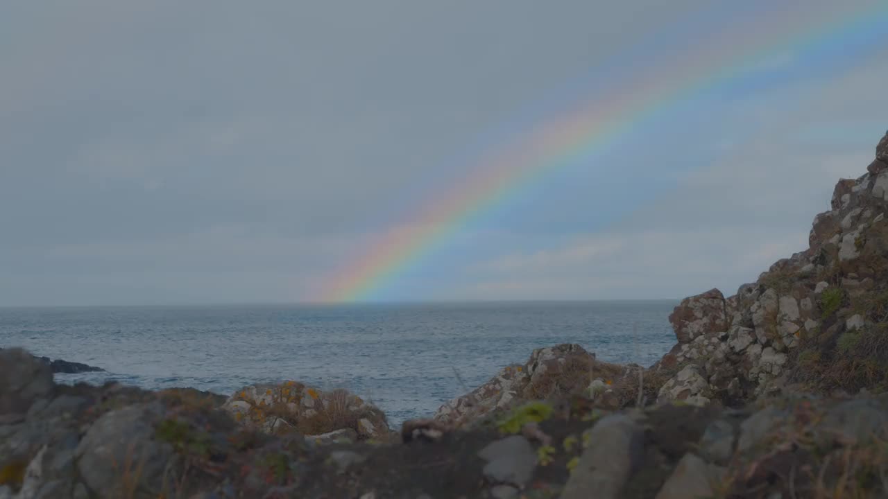 彩虹在岩石海岸进入海洋视频素材