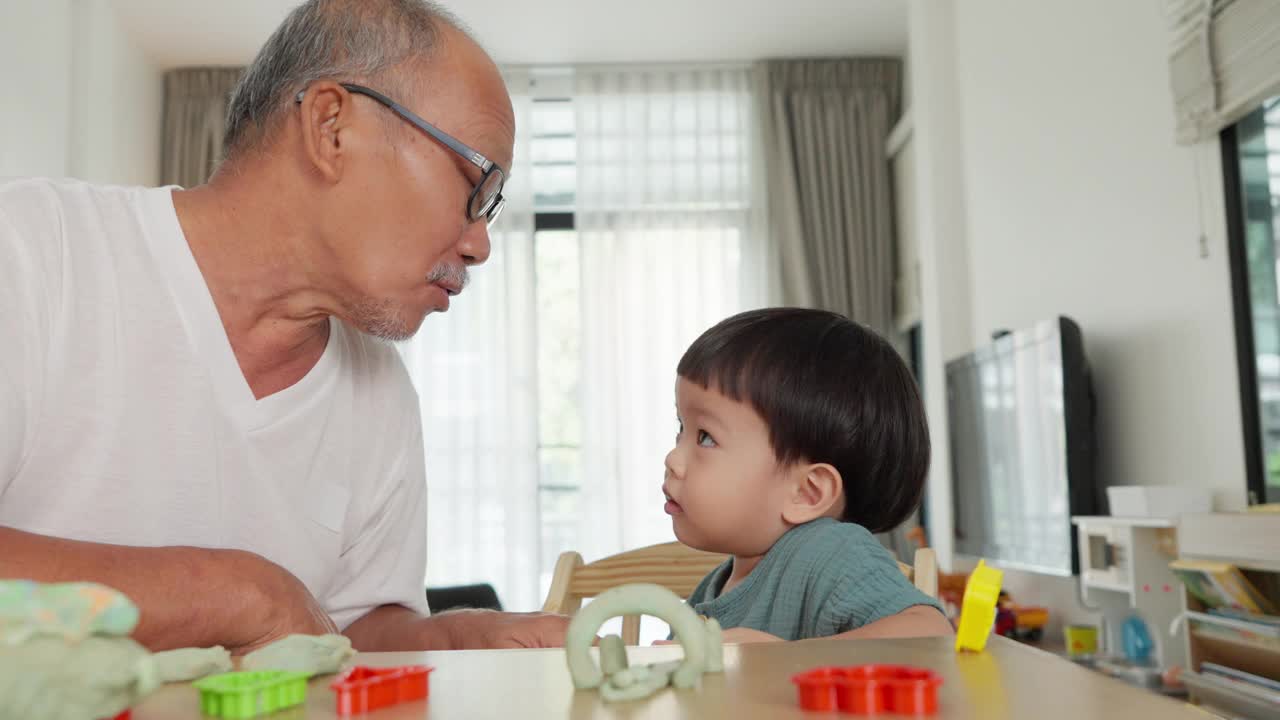 爷爷和孙子用橡皮泥制作玩具。视频素材