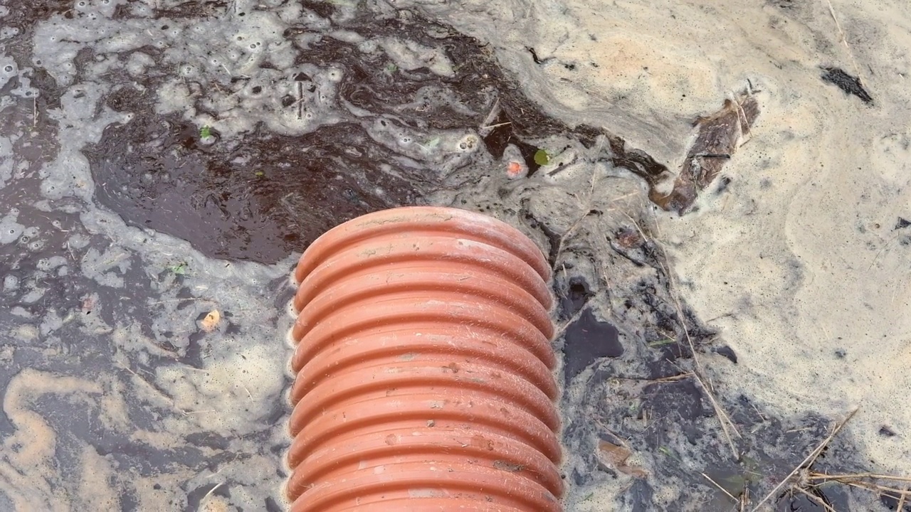 排水管内有水流流动。雨水管理在公共空间，塑料管，岩石和灌木种植。污水系统的塑料管。地下管道系统。视频素材