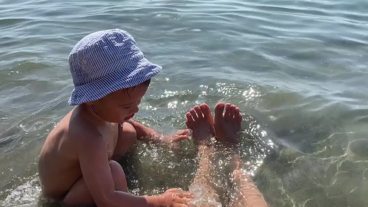 戴着巴拿马帽子的快乐小男孩在海里玩耍的特写视频素材