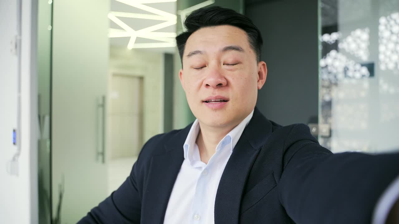 POV Webcam view. Close up of an asian businessman talking on a video call using a smartphone at a workplace in a modern office.视频素材