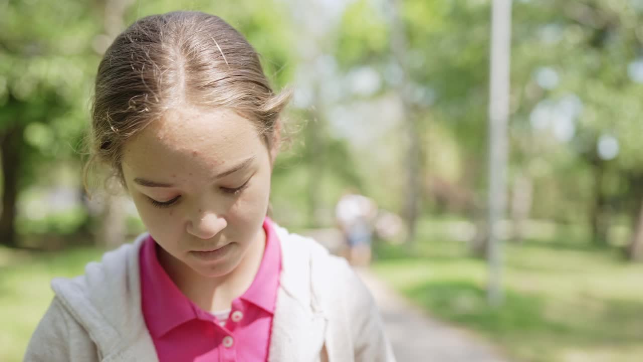 一个十几岁的女孩戴着头盔在公园里骑自行车视频素材