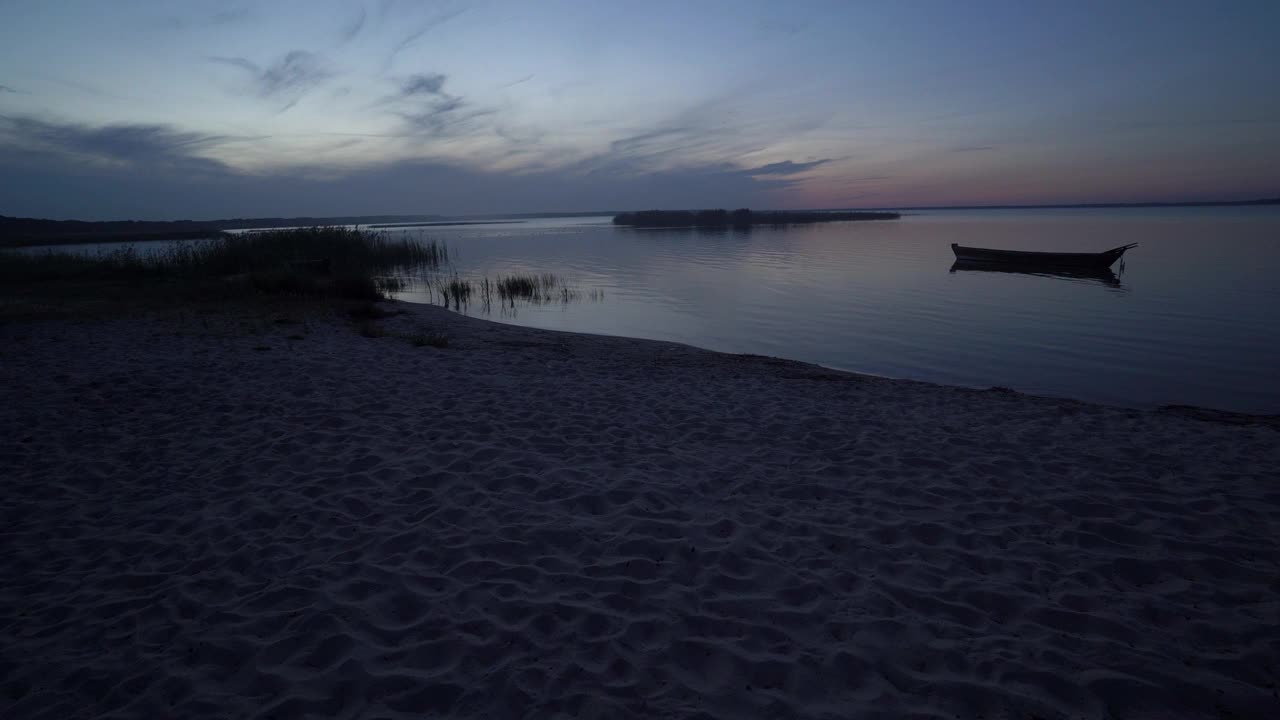 傍晚或夜间沿着海岸、海滩、芦苇、渔船和岛屿在日出或日落后在乌克兰的斯维提亚茨湖全景航行。视频素材