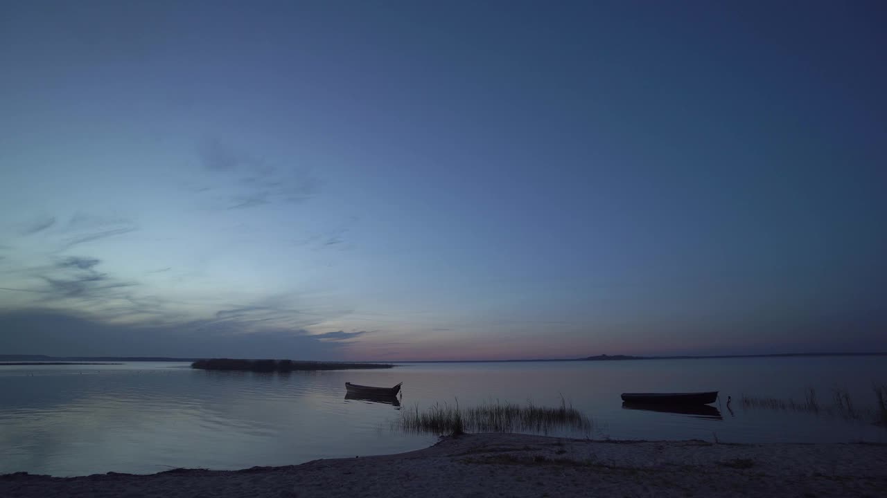 美丽的傍晚或夜间景观与海岸，海滩，芦苇，渔船和岛屿在日出或日落后的Svityaz湖，乌克兰。视频素材