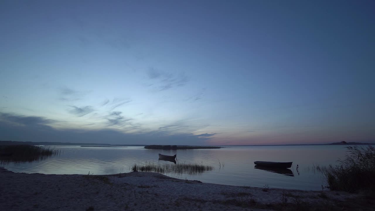 美丽的傍晚或夜间景观与海岸，海滩，芦苇，渔船和岛屿在日出或日落后的Svityaz湖，乌克兰。视频素材